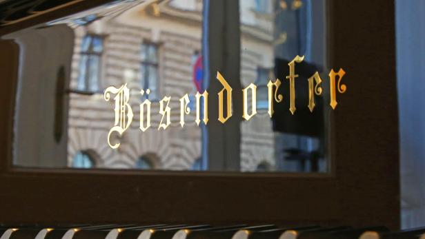 Ein Klavier der Marke Bösendorfer mit goldenem Schriftzug und Spiegelung eines Gebäudes.