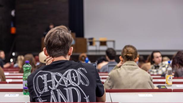 Mehrere Studierende sitzen in einem Hörsaal und blicken zur Tafel nach vorne.