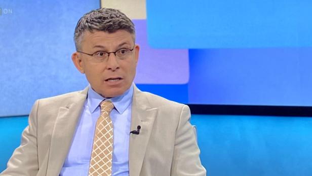 Ein Mann im hellen Anzug in einem TV-Studio