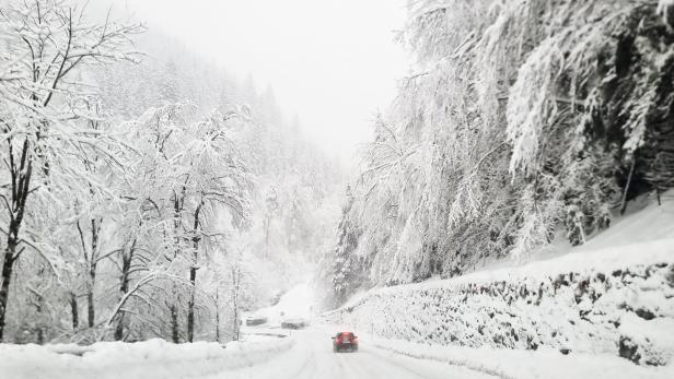 Ein Auto fährt auf der verschneiten Loiblpass-Bundesstraße.