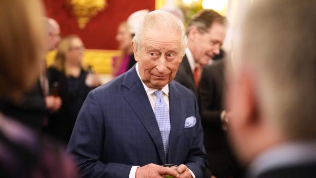 König Charles III. hält ein Getränk in einem formellen Rahmen.