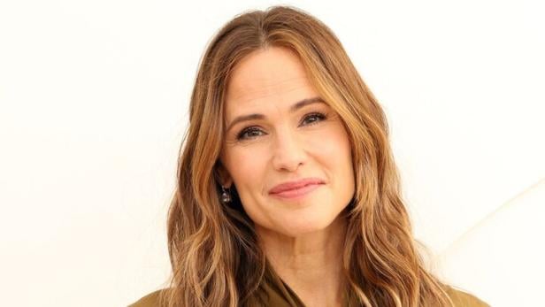 Jennifer Garner trägt eine olivgrüne Bluse mit Schleife und einen schwarzen Rock.