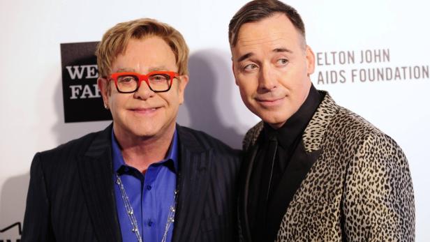 Elton John und David Furnish posieren zusammen auf einer Veranstaltung.