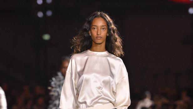 Weißes Satin-„T-Shirt“ zum exzentrischen Rock mit weißen Federn. 