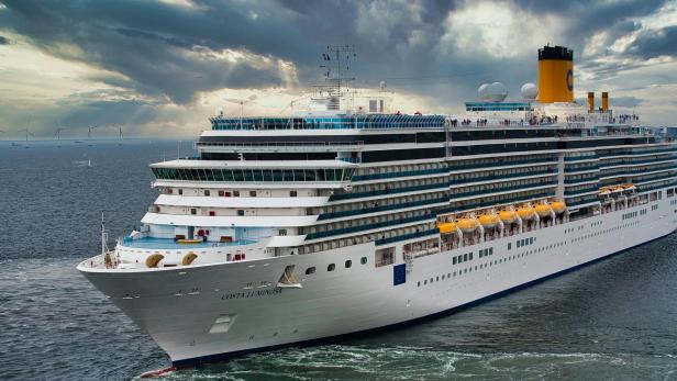 weißes Kreuzfahrtschiff auf See unter weißen Wolken und blauem Himmel
