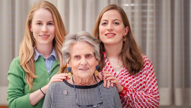 Drei Frauen unterschiedlichen Alters posieren lächelnd für ein Porträt.