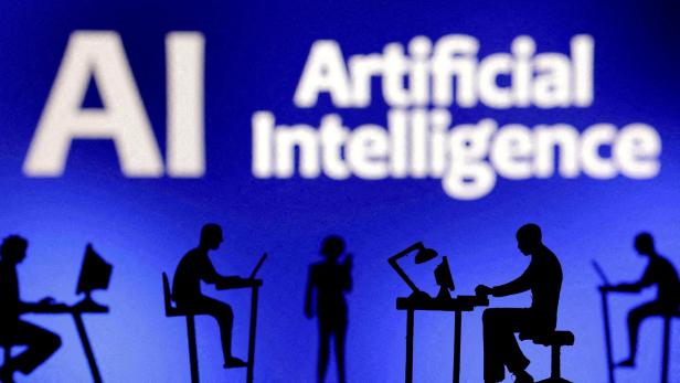 Mehrere Personen arbeiten an Computern vor einem blauen Hintergrund mit der Aufschrift „Artificial Intelligence“.