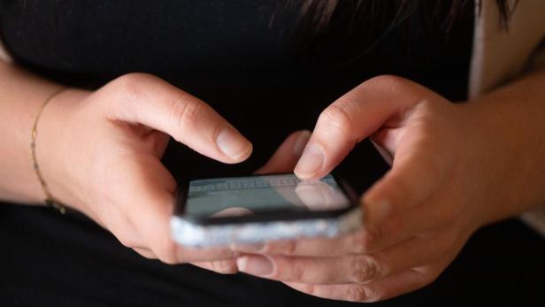 Zwei Hände halten ein Smartphone und tippen auf dem Bildschirm.