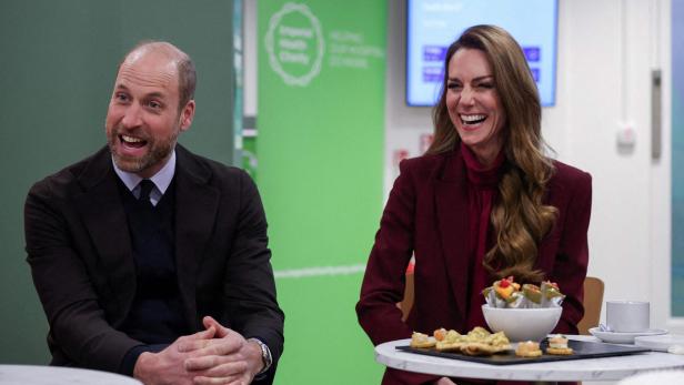 Prinz William und Prinzessin Kate lachen an einem Tisch mit Snacks.
