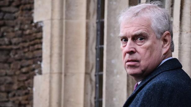 Andrew Mountbatten-Windsor blickt über die Schulter, im Hintergrund eine Steinmauer.