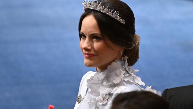 Prinzessin Sofia von Schweden mit Tiara und hellem Kleid mit Blumenapplikationen blickt zur Seite.
