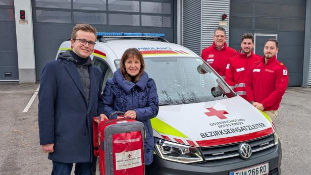 Fünf Personen stehen neben einem Rettungsfahrzeug