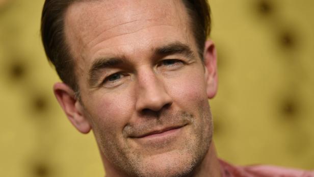 James Van Der Beek lächelt vor unscharfem gelbem Hintergrund.