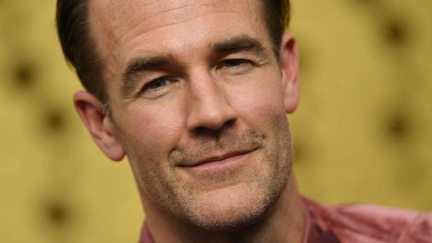 James Van Der Beek lächelt vor unscharfem gelbem Hintergrund.