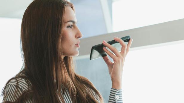 Eine Frau hält ein Handy in der Hand und spricht