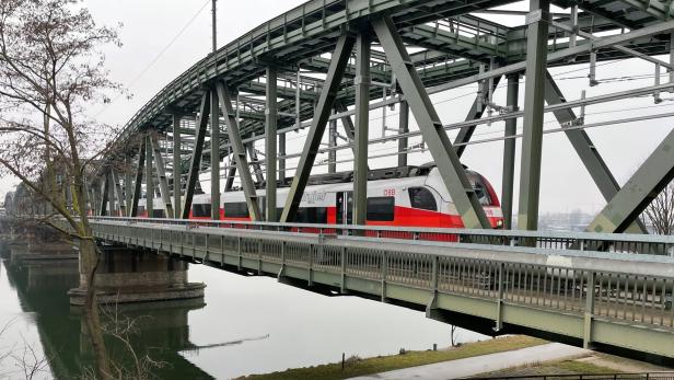 Eine Garnitur der ÖBB-Schnellbahn fährt über die Donaubrücke.