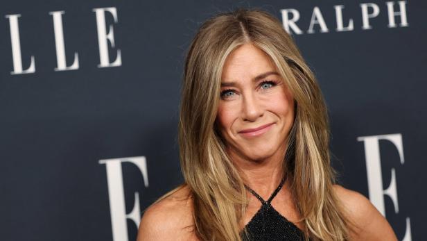 Jennifer Aniston lächelt vor einem dunklen Hintergrund.