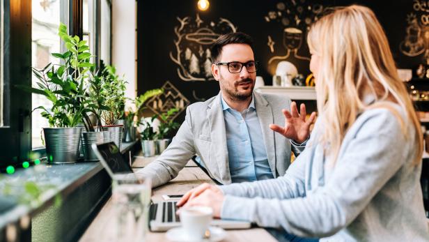 Handsome man talking to a young blonde woman at the cafe.