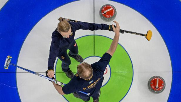 schwedisches Curling-Duo Isabella und Rasmus Wranå steht am Eis und ist kurz davor, sich zu umarmen