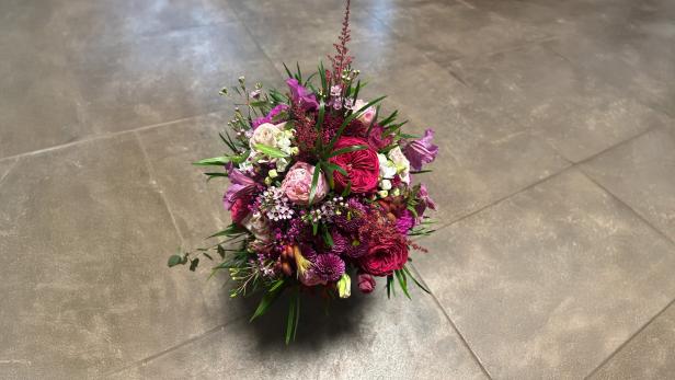 Ein bunter Blumenstrauß steht auf dem Boden. 