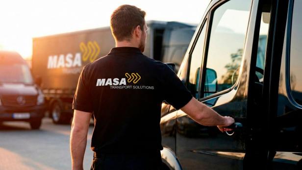 Mitarbeiter von MASA Transport Solutions öffnet die Tür eines Lieferwagens bei Sonnenuntergang.