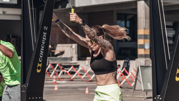 Frau trainiert an einem Ski-Ergometer im Freien bei sonnigem Wetter.