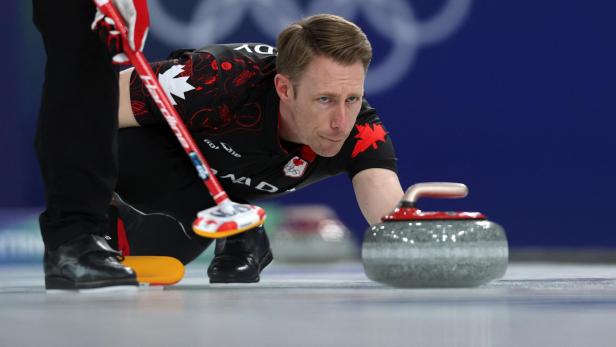 Ein kanadischer Curler lässt einen Curlingstein auf dem Eis gleiten.