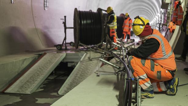 Arbeiter in orangener Kleidung bei den Arbeiten im Tunnel.