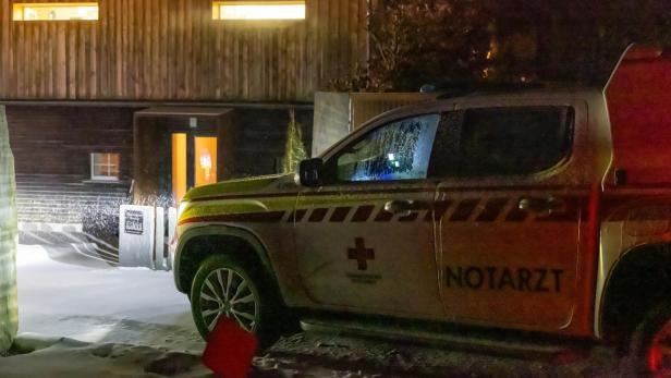 Ein Notarztfahrzeug steht nachts vor einem beleuchteten Gebäude im Schnee.