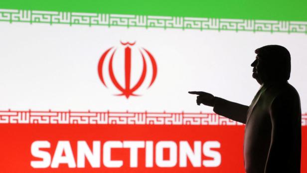 Eine Silhouette von Donald Trump deutet auf Sanktionen vor der iranischen Flagge.