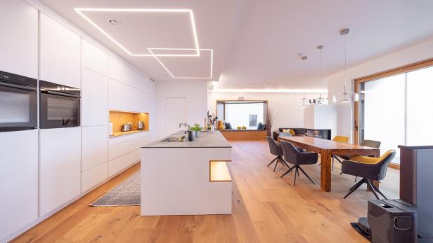 Moderne offene Wohnküche mit Essbereich, Holzboden und minimalistischer Einrichtung.