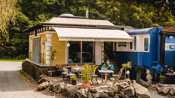 Ein gelbes Häuschen bei einem blauen Waggon 