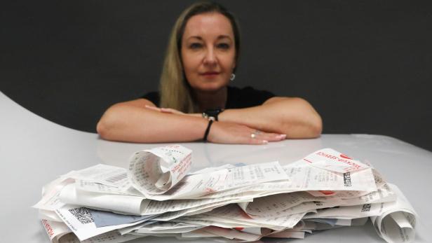 Blonde Frau im Hintergrund schaut auf einen Berg an Kassazettel im Vordergrund