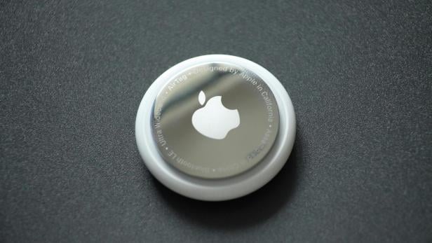 Ein Apple AirTag liegt auf einer dunklen Oberfläche und zeigt das silberne Apple-Logo in der Mitte.
