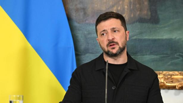 Wolodymyr Selenskyj spricht vor der Flagge der Ukraine am Rednerpult des Bundeskanzleramts.