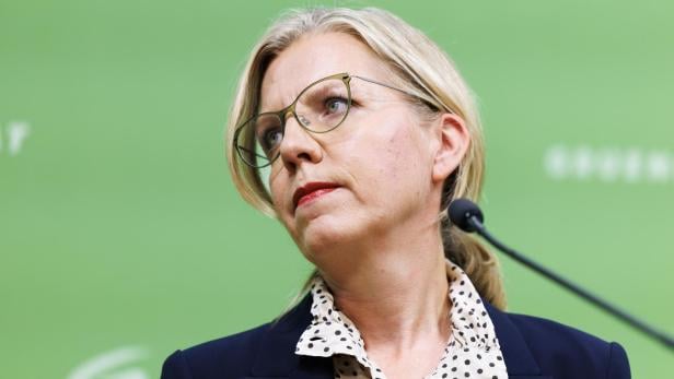 Leonore Gewessler steht vor einem grünen Hintergrund.