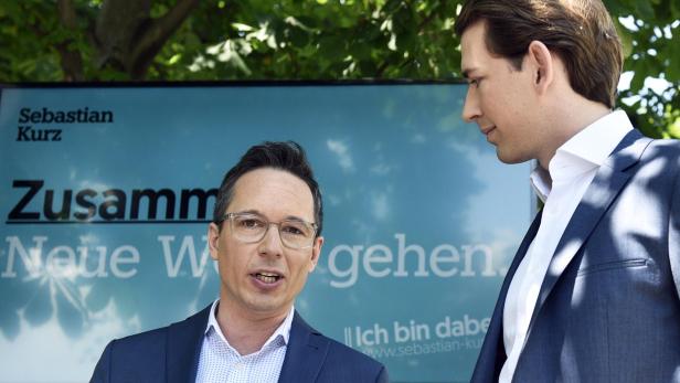 Zwei Männer stehen vor einem Wahlplakat von Sebastian Kurz.