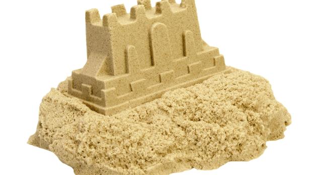 Eine Sandburg mit Zinnen steht auf einem Haufen Sand.