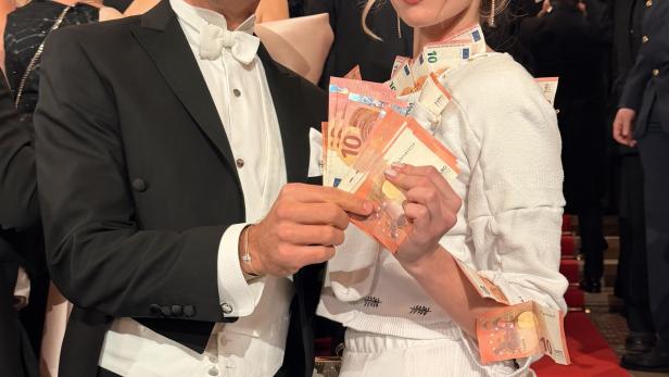 Max Weißenböck und seine Mitarbeiterin Joanna präsentieren beim Opernball ein Kleid, das mit 10-Euro-Scheinen geschmückt ist.