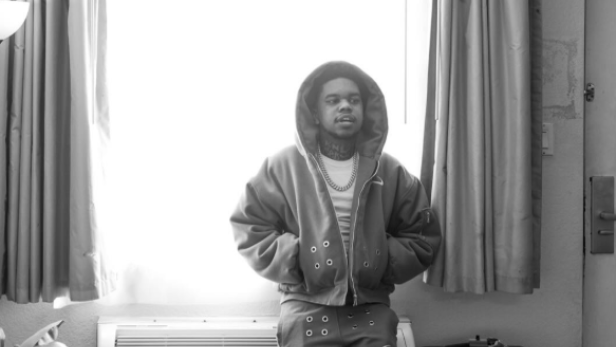 Mann mit Hoodie-Kapuze auf dem Kopf lehnt gegen Heizkörper am Fenster