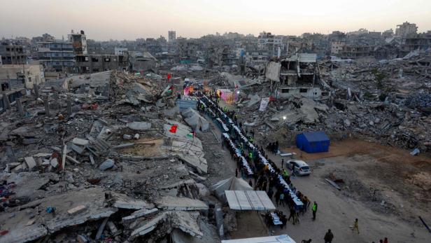  Palästinenser versammeln sich am 18. Februar 2026 inmitten der Trümmer zerstörter Gebäude in Gaza-Stadt zu einem von der türkischen IHH-Stiftung organisierten gemeinsamen Fastenbrechen (Iftar).