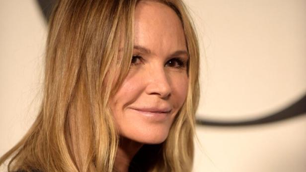 Elle Macpherson mit blonden Haaren und dunkler Jacke lächelt in die Kamera.