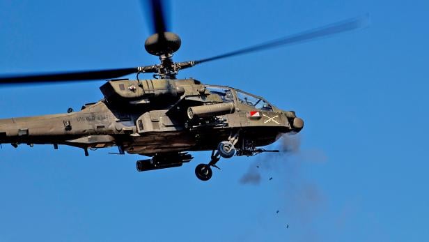 Kampfhubschrauber AH-64 Apache feuert seine 30-mm-Kanone im Flug ab.