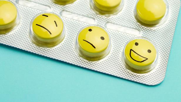 Yellow pills andfunny faces in a blister on a blue background.