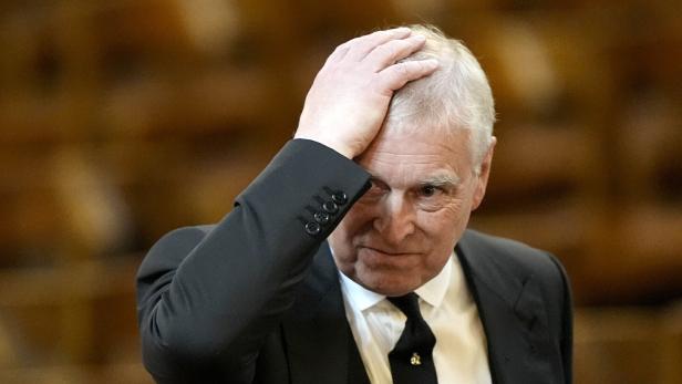 Ex-Prinz Andrew Mountbatten-Windsor hält sich die Hand an die Stirn und trägt einen dunklen Anzug.