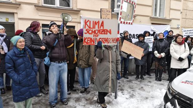 Mehrere Personen im verschneiten Wien demonstrieren für die Angeklagten.