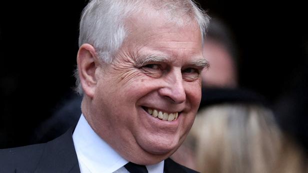 Andrew Mountbatten-Windsor lächelt mit grauem Haar und dunklem Anzug.