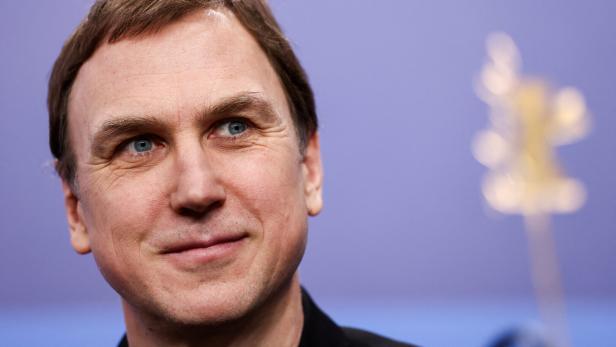 Lars Eidinger mit hellbraunen Haaren und blauen Augen blickt lächelnd nach oben.