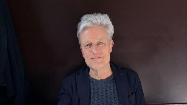 Florian Scheuba sitzt an einem gedeckten Tisch