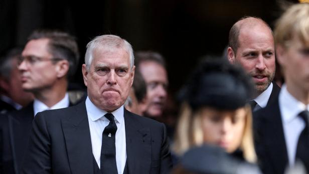 Prinz Andrew und Prinz William in dunklen Anzügen inmitten einer Menschenmenge.